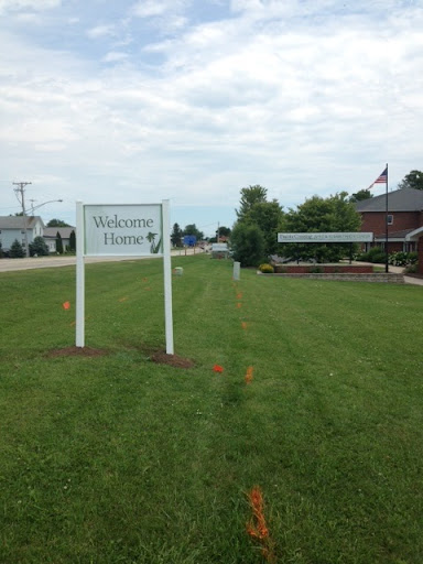 A welcoming sign in a grassy area, indicating the entrance to a facility.