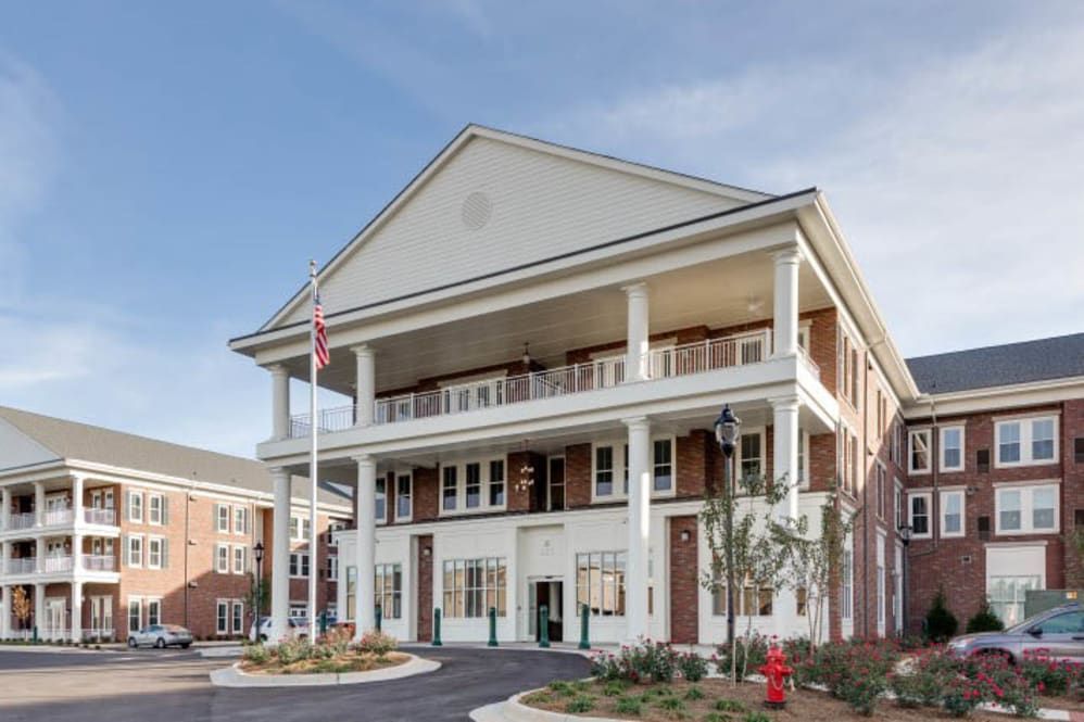 A colonial-style building with a prominent entrance and balconies, featuring a flagpole in front.