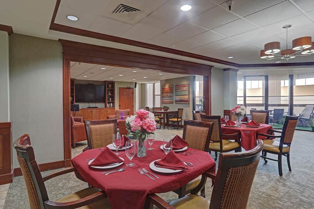 An elegantly set dining room with red tablecloths and floral centerpieces.
