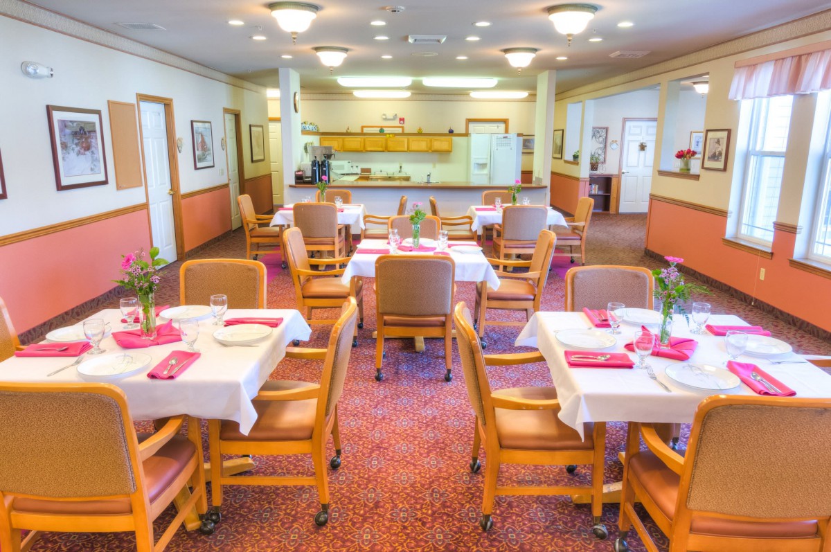 A well-lit dining room with neatly arranged tables and chairs, ready for service.
