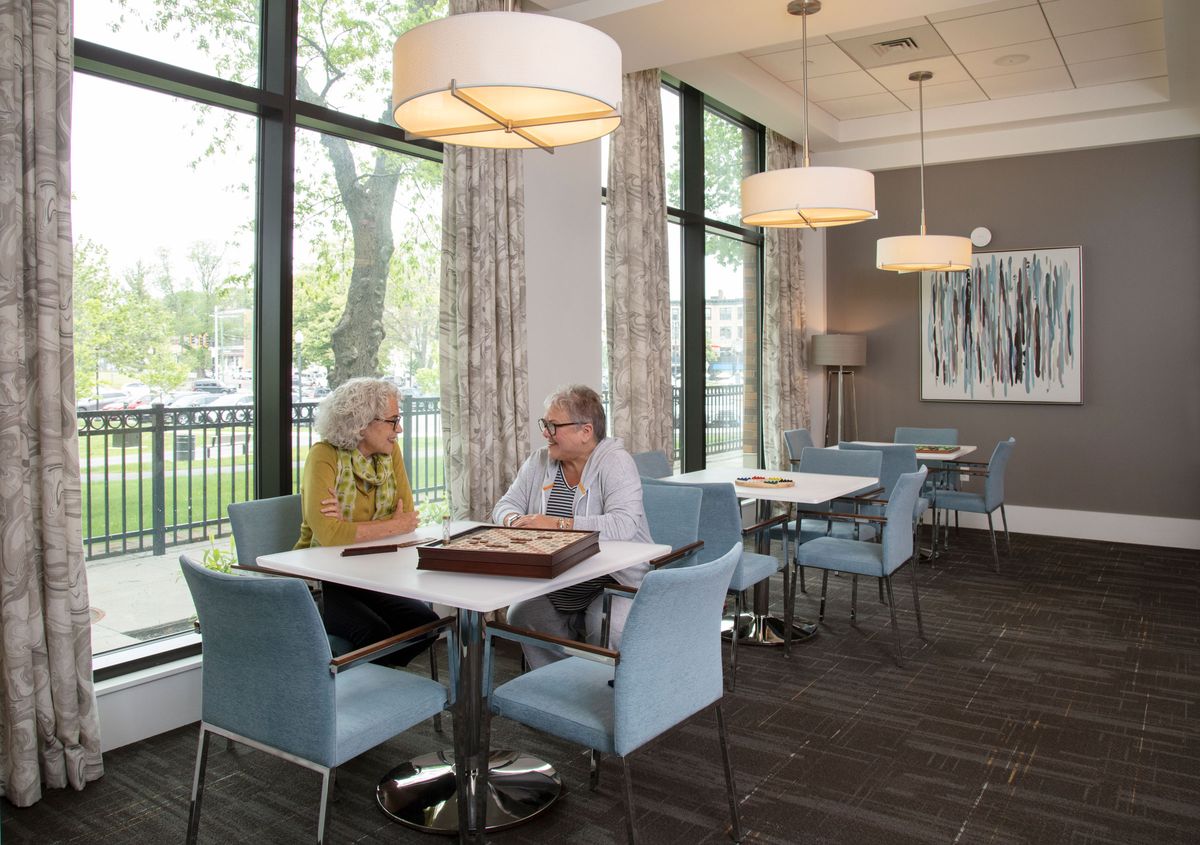 Two seniors engaged in conversation at a modern, well-lit indoor setting.