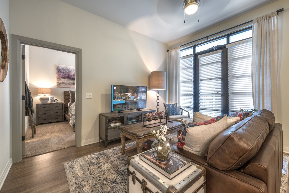A modern living room with comfortable seating, a TV, and large windows.