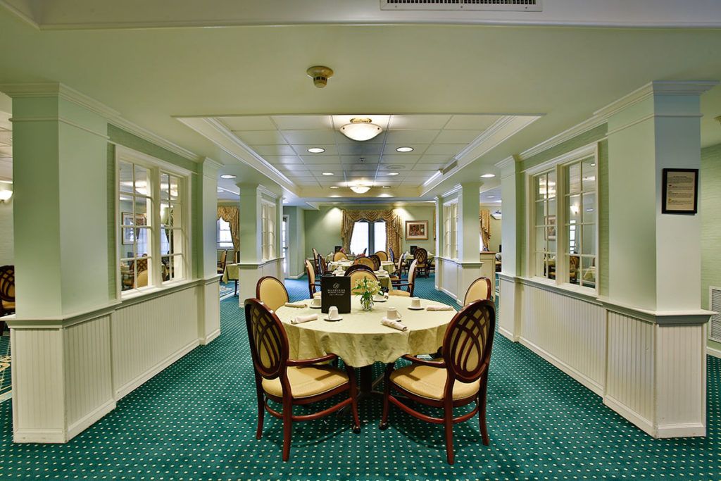 A formal dining area with elegantly set tables and upholstered chairs on a carpeted floor.