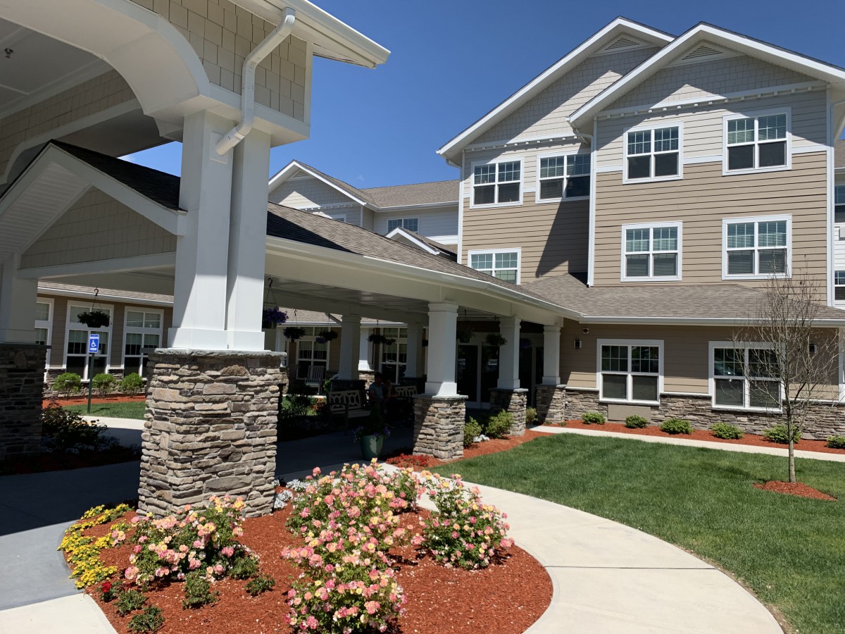 A modern residential building with well-maintained landscaping and a clear blue sky.