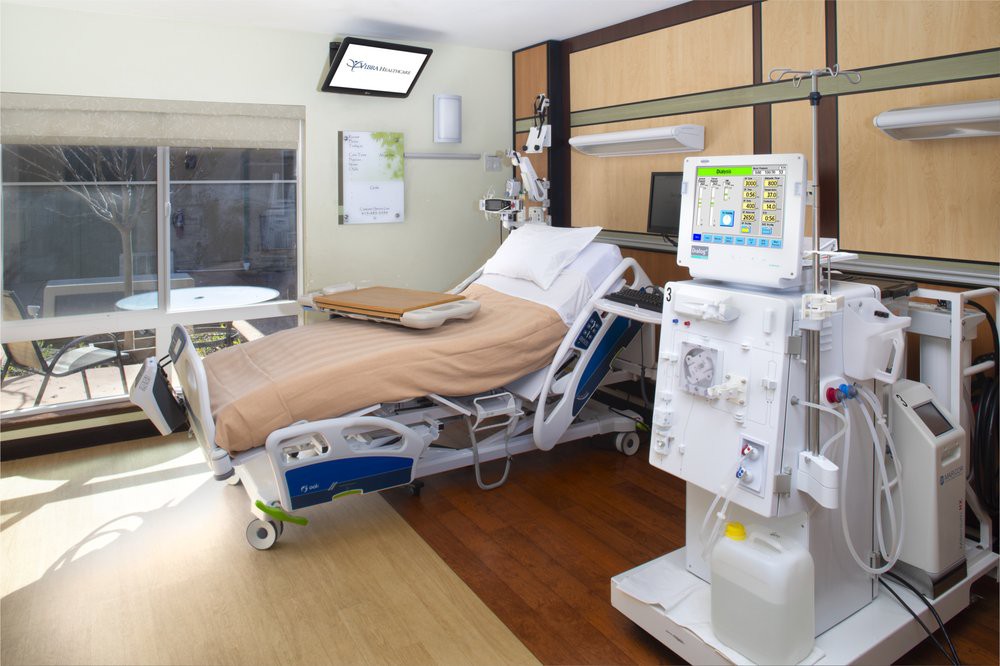 A modern hospital room equipped with a dialysis machine and an adjustable hospital bed.