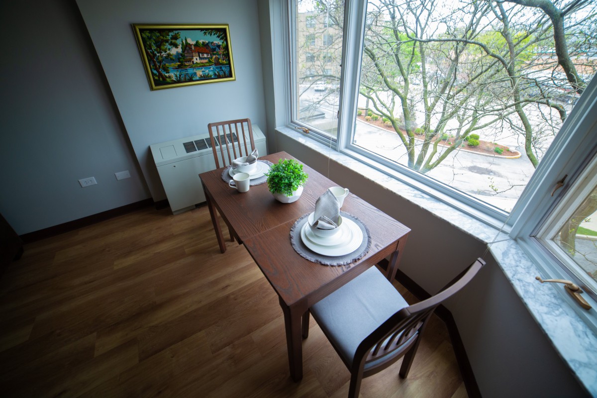 A cozy dining area with a wooden table set for two near a large window.