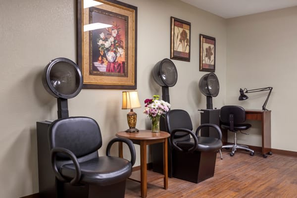 A cozy salon waiting area featuring hair dryers, comfortable chairs, and decorative wall art.
