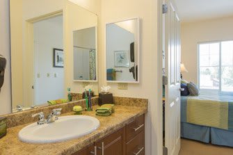 A clean and well-organized bathroom with a sink, mirror, and neatly arranged towels.
