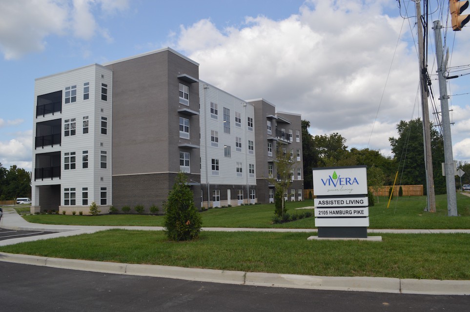 A modern apartment complex with a sign in front and well-maintained landscaping.