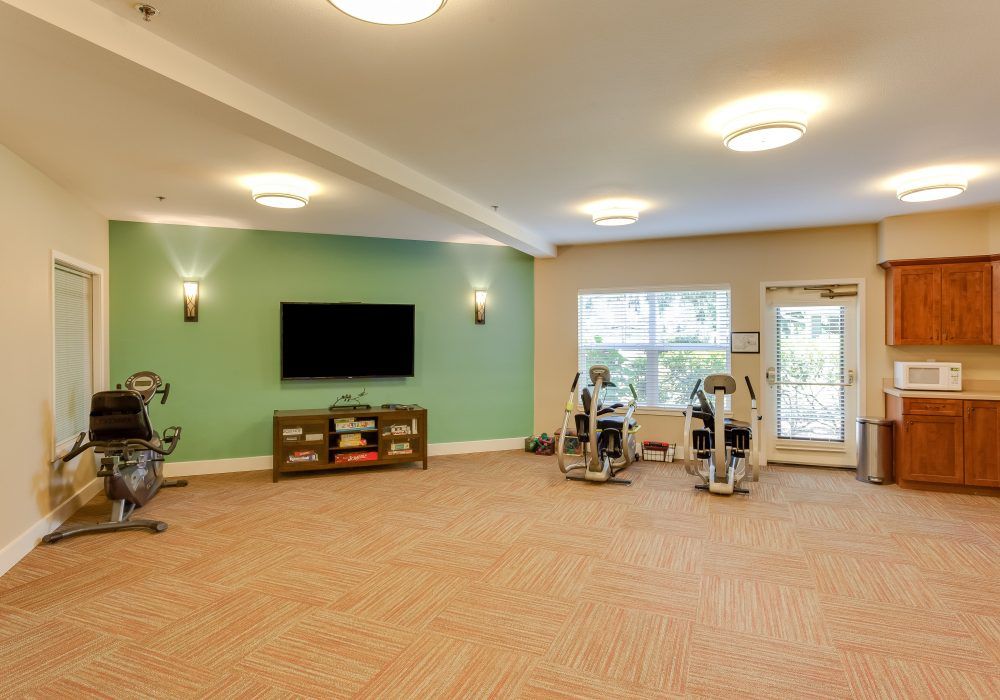 A spacious gym with exercise equipment and a television.