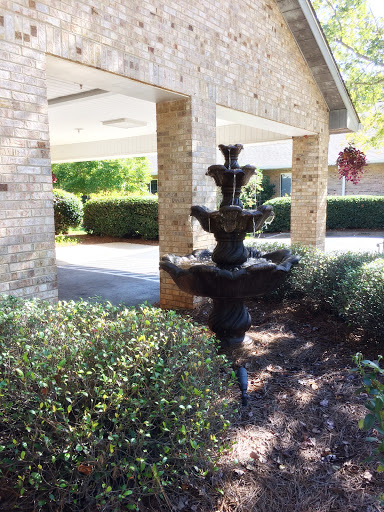 A tranquil garden scene featuring a decorative fountain surrounded by lush greenery.