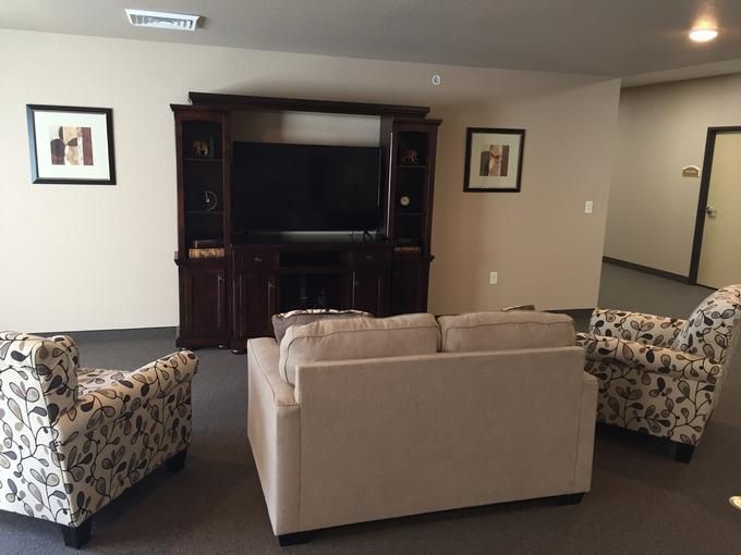 A cozy living room setup featuring comfortable seating and a large television in an entertainment unit.