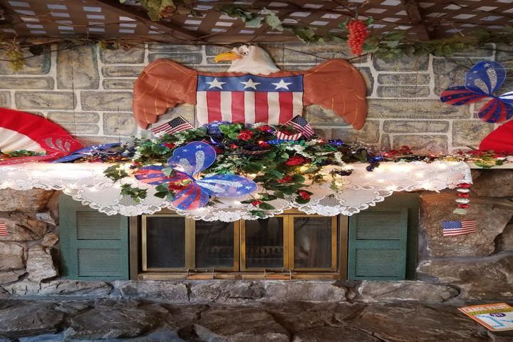 A patriotic-themed decoration above a fireplace featuring an eagle with an American flag motif and a colorful floral arrangement.