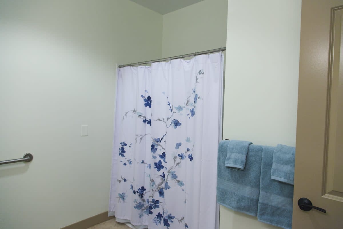 A bathroom with a floral patterned shower curtain and neatly hung towels.