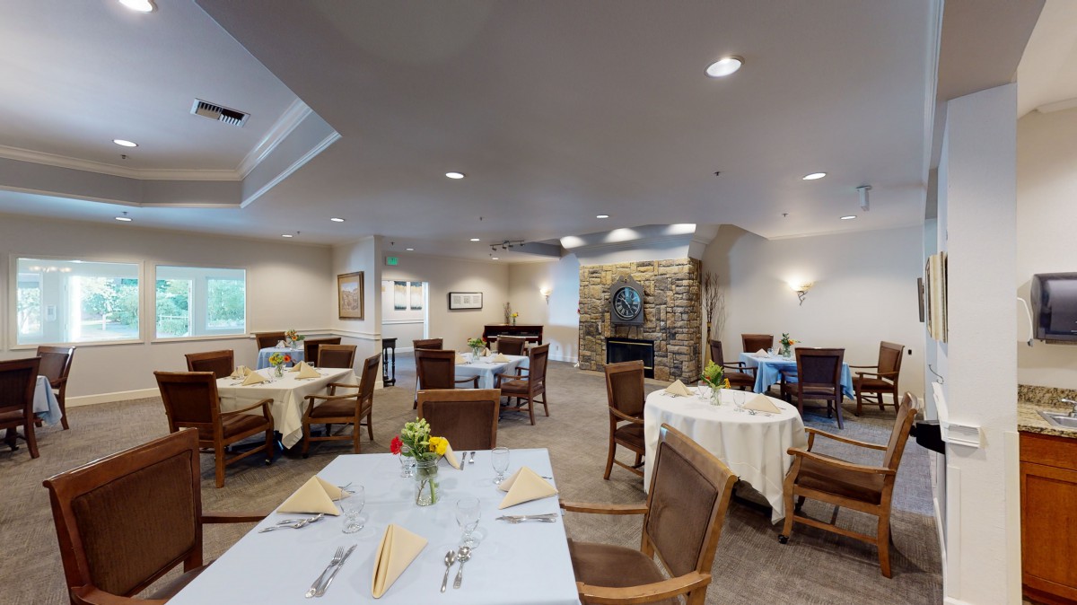 A cozy dining room with neatly arranged tables and chairs, featuring warm lighting and decor.
