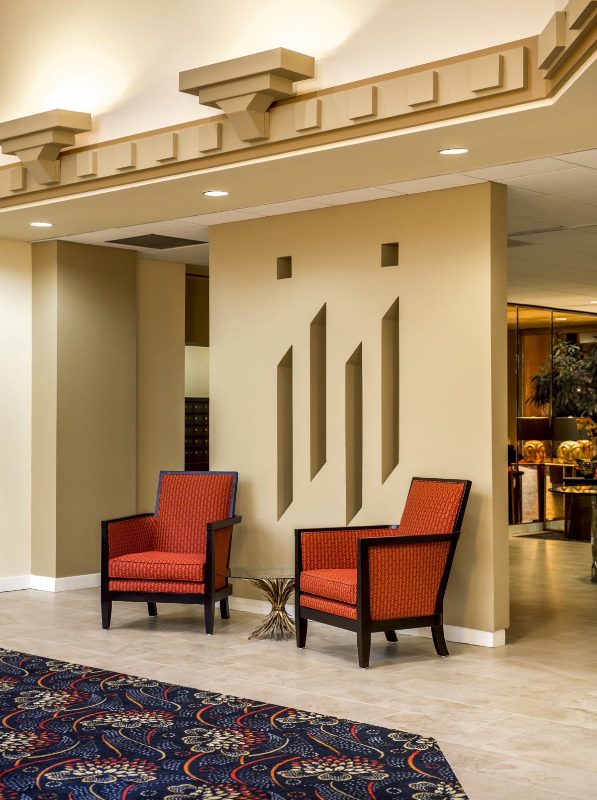 A modern interior with two red chairs in a well-lit lobby area.