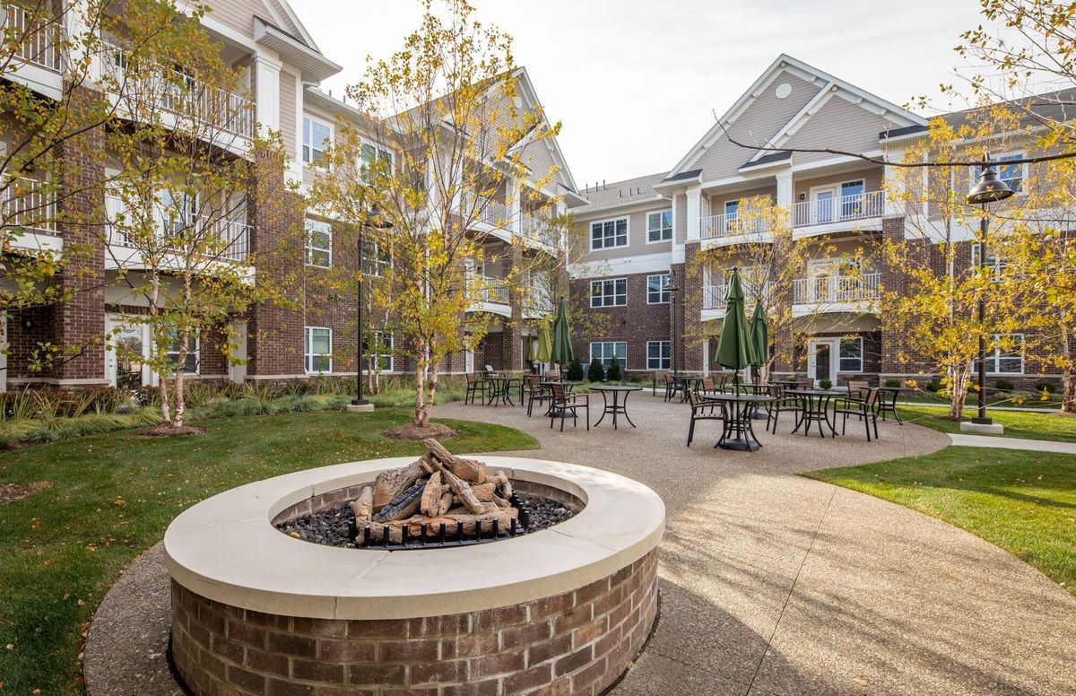 A cozy outdoor area with a fire pit and patio furniture surrounded by an apartment complex.