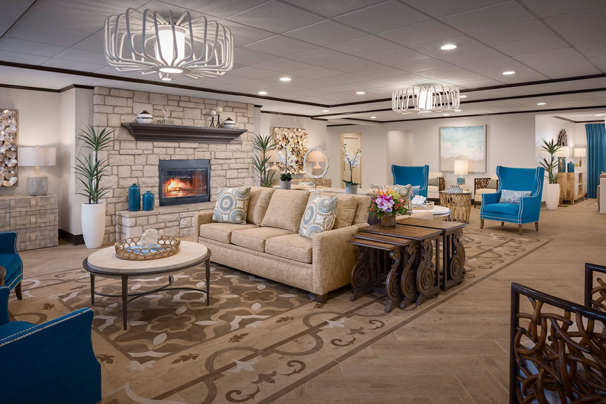 A beautifully decorated living room featuring a cozy sofa, elegant chandeliers, and a warm fireplace.