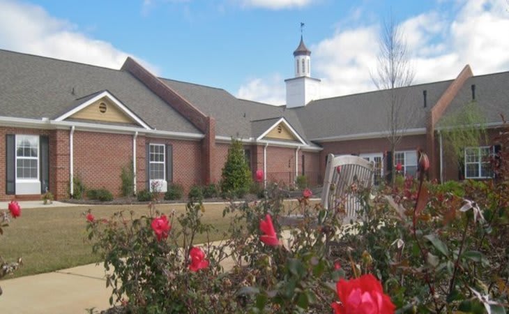 A charming church building with a garden of vibrant red flowers in the foreground.
