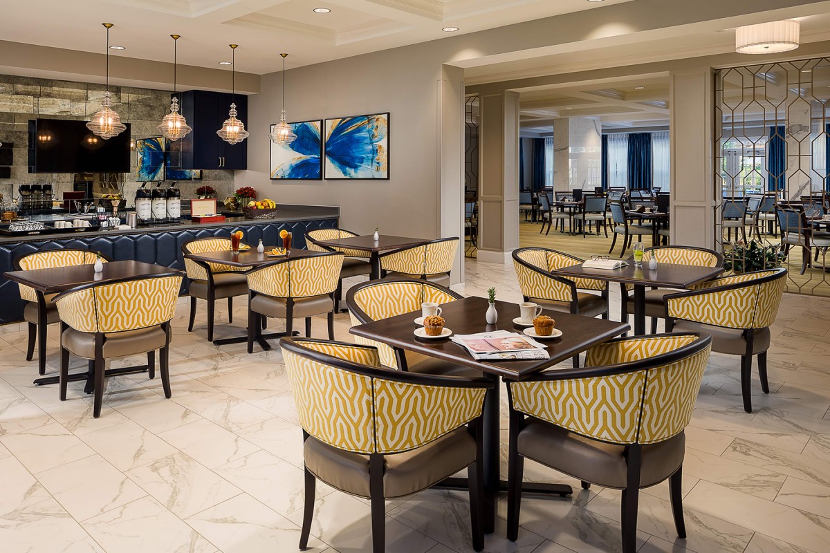 A modern restaurant interior with neatly arranged seating and contemporary artwork on the wall.