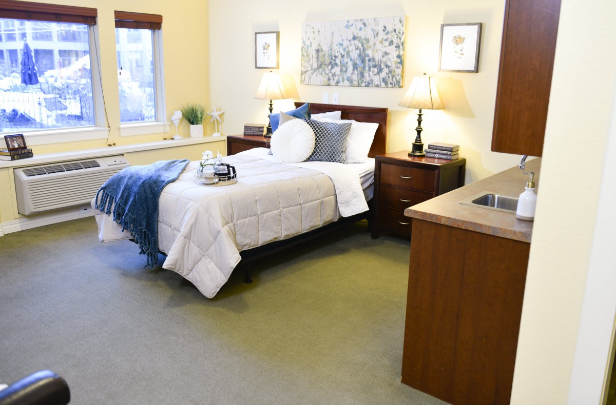 A cozy bedroom with a neatly made bed, bedside tables, lamps, and wall art.