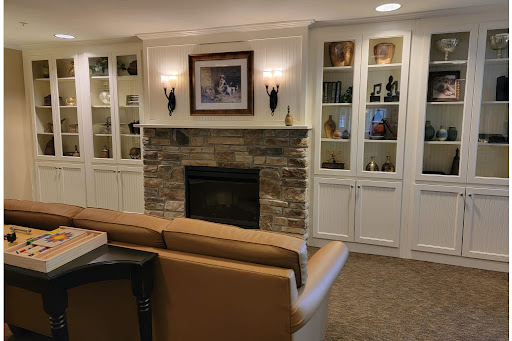A cozy living room featuring a stone fireplace and elegant shelving.