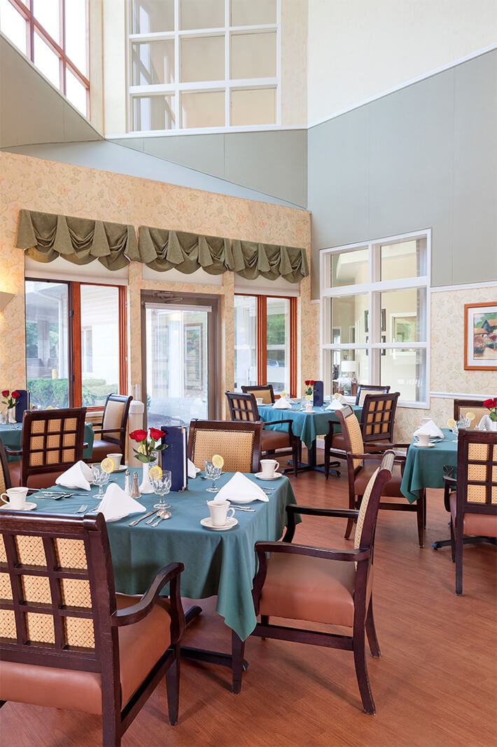 A cozy, well-lit dining room with elegantly set tables and comfortable chairs.