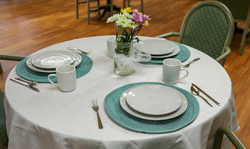 A beautifully arranged dining table featuring floral centerpieces, elegant plates, and mugs.