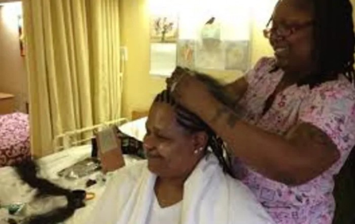 A woman getting her hair braided in a salon setting, smiling as she enjoys the service.