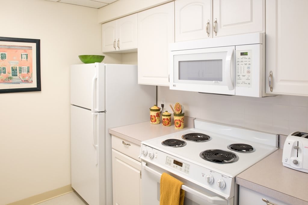 A modern kitchen with white cabinets, featuring a refrigerator, stove, and microwave.