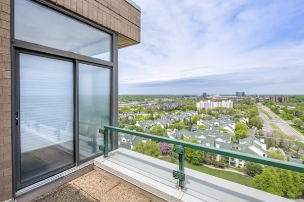 A balcony view showcasing a cityscape with greenery and distant buildings under a blue sky.