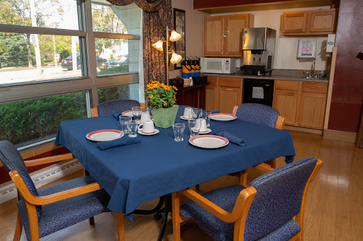 A cozy dining area featuring a well-set table with a blue tablecloth and decorative flowers.