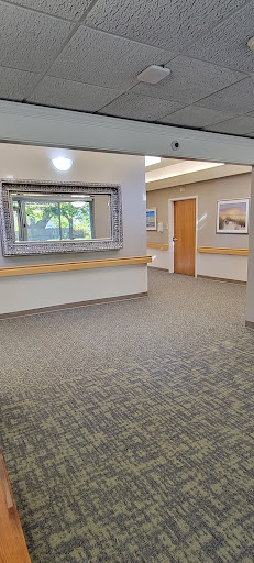 A well-lit hospital hallway featuring a decorative mirror and artwork on the walls.
