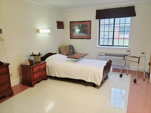 A well-lit hospital room featuring a bed, bedside table, and a window.