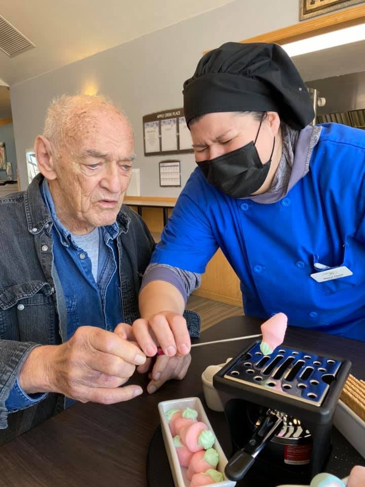 An elderly man and a chef work together on a culinary project.