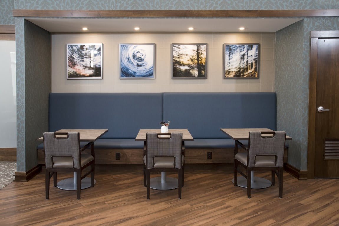 A modern dining area in a restaurant featuring tables and chairs, with artwork on the walls and subtle lighting.