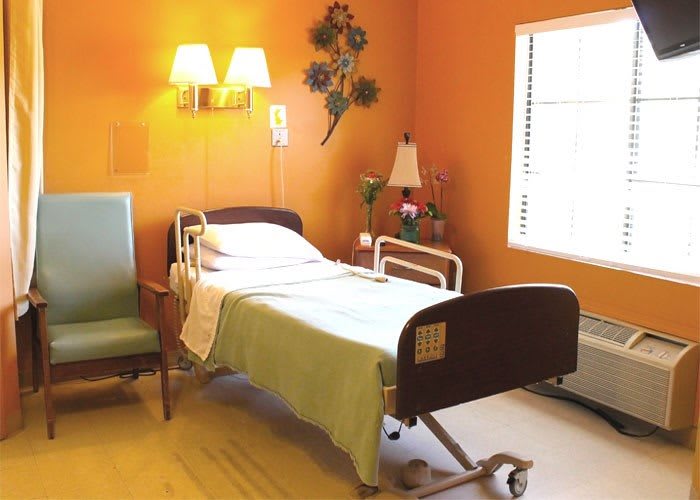 A well-lit hospital room with a single bed, chair, and decorative elements.
