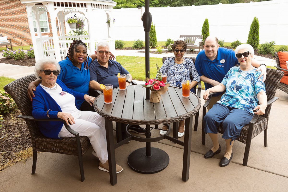 A group of seniors enjoying drinks together on a patio during a social gathering.
