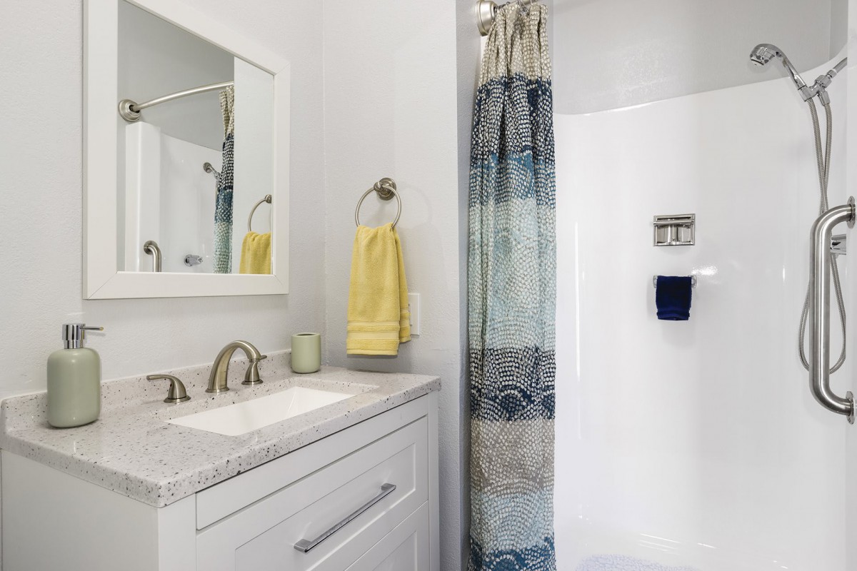 A modern bathroom with a shower, vanity with mirror, and decorative towels.