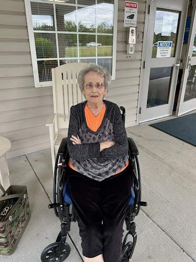 An elderly woman sitting comfortably in a wheelchair, enjoying the outdoors.