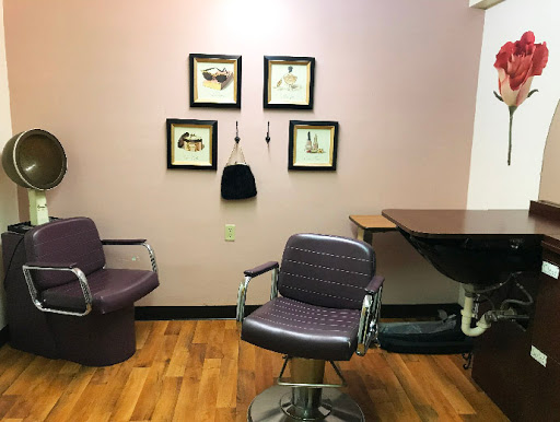 A cozy corner of a hair salon featuring stylish chairs and framed artwork on the wall.