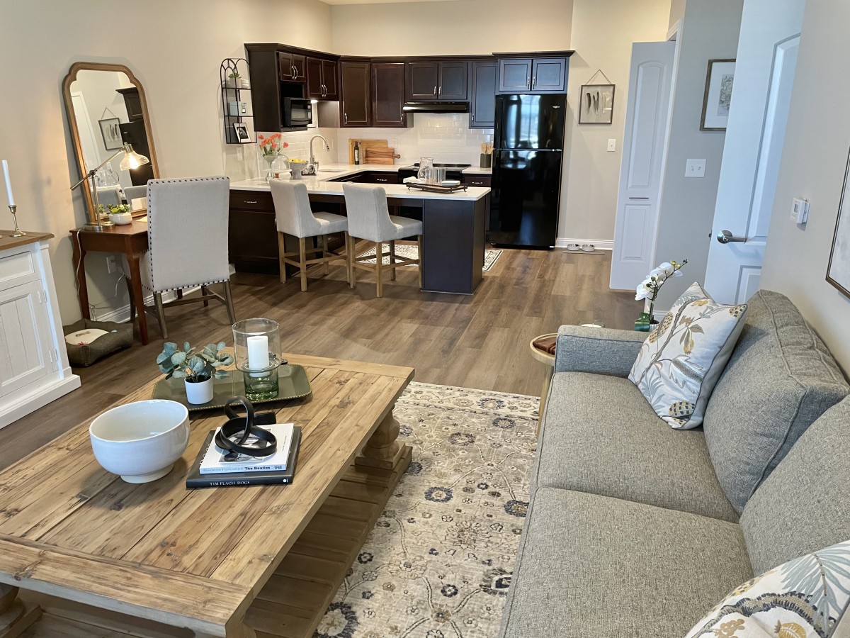 A modern open-floor living room and kitchen with stylish furniture and wooden flooring.