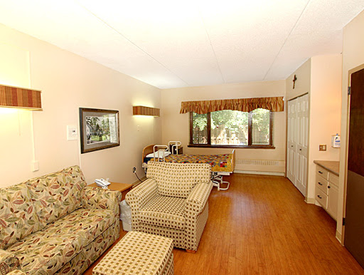 A cozy living room featuring a sofa and armchair, complemented by natural light streaming through the windows.