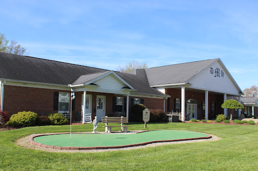 A well-maintained residential building featuring a small golf putting green and a beautiful lawn under a clear blue sky.