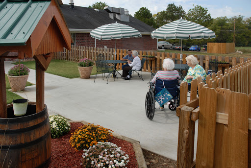 Elderly individuals enjoying a peaceful afternoon in a garden setting at a care facility.