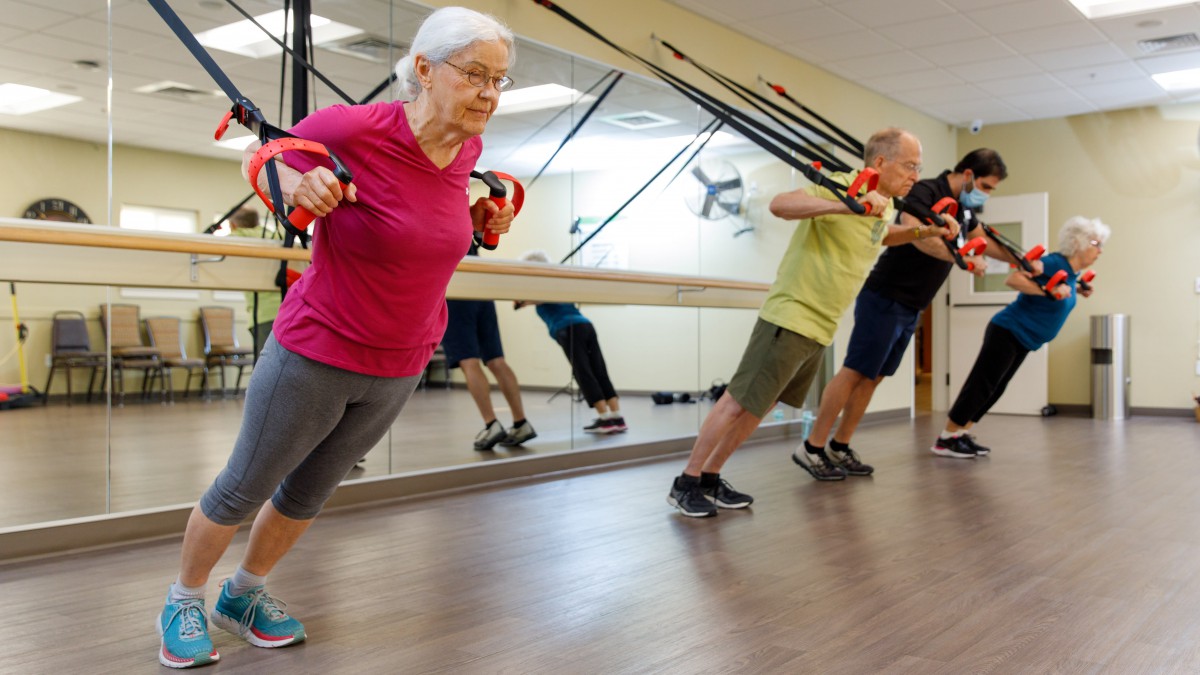 Seniors engaging in a TRX workout session at the gym.