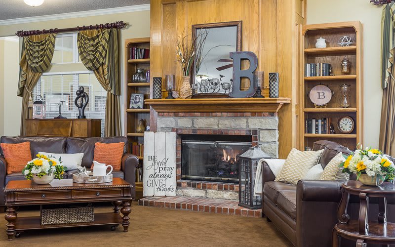 A cozy living room with a central fireplace, surrounded by decor and bookshelves.