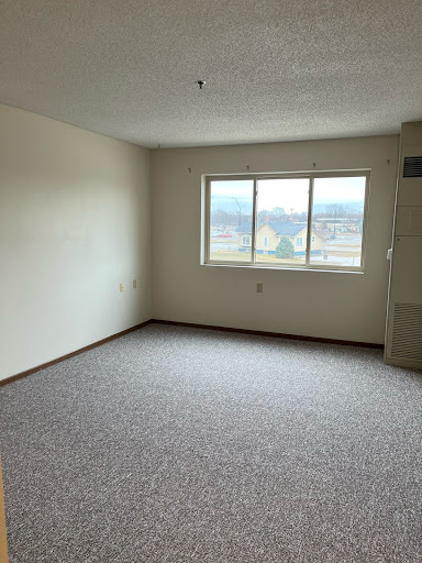 A spacious empty room with a window allowing natural light.