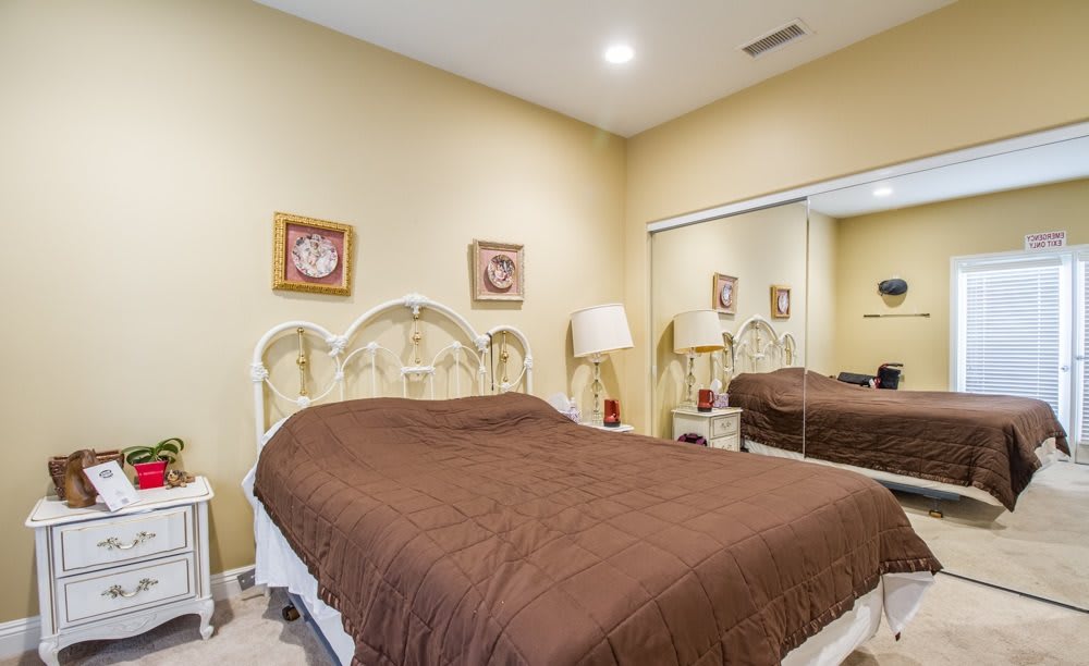 Cozy bedroom with a brown bedspread, mirrored closet, and warm beige walls.
