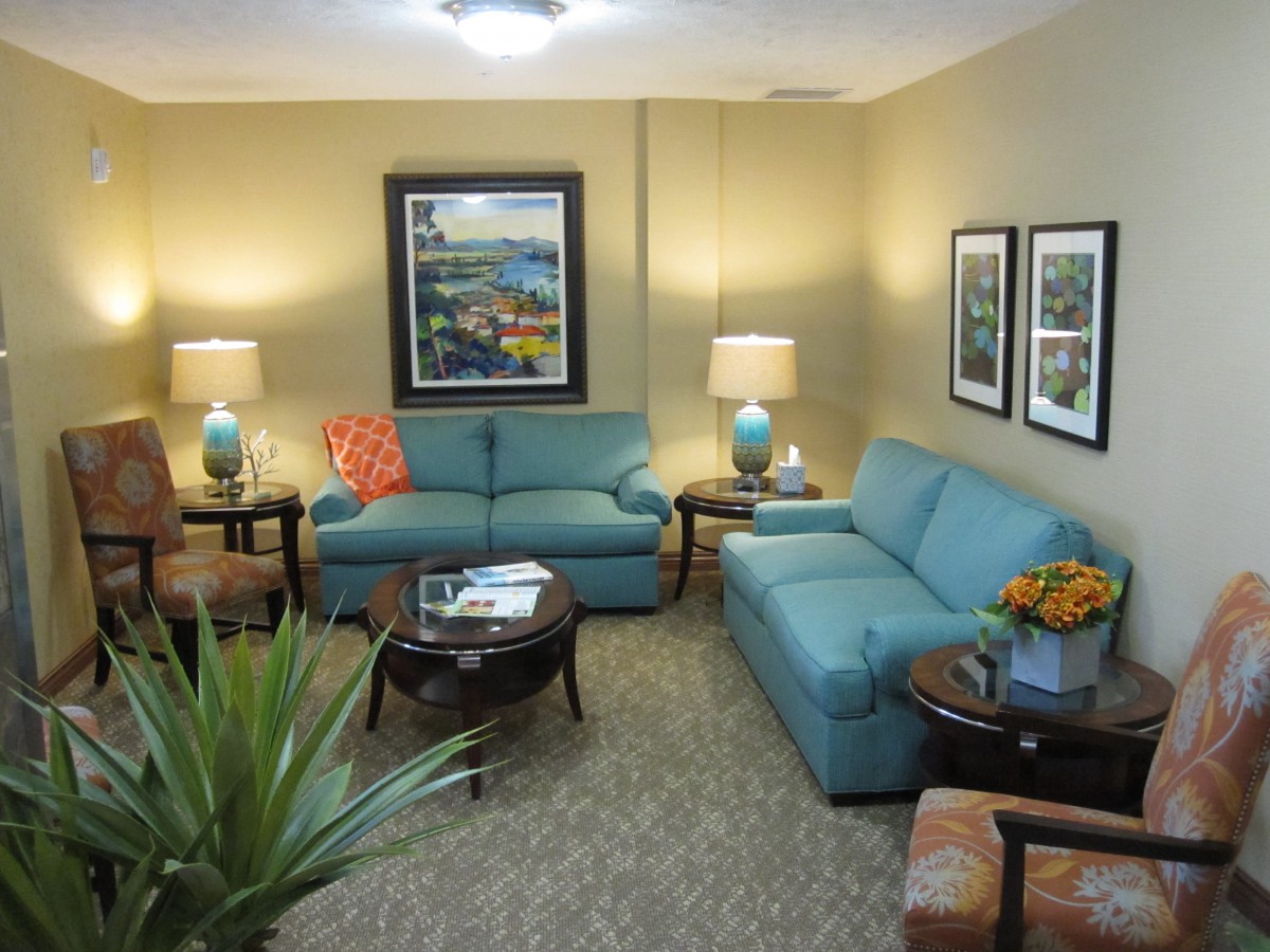 A cozy living room with blue sofas, table lamps, and decorative elements.